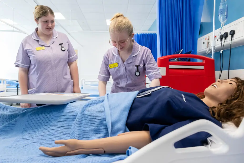 Two students in nursing uniform at the health care ward in Salisbury Wiltshire College & University centre working on a dummy.