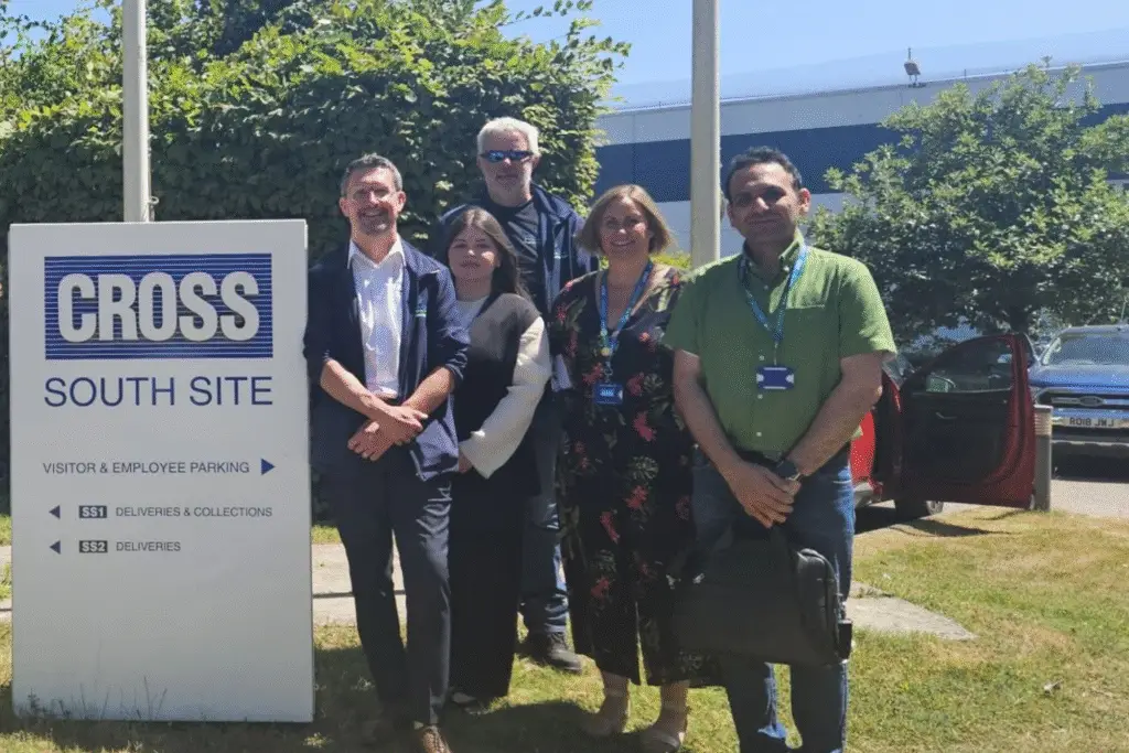 A group of staff standing together by the Cross Manufacturing sign.