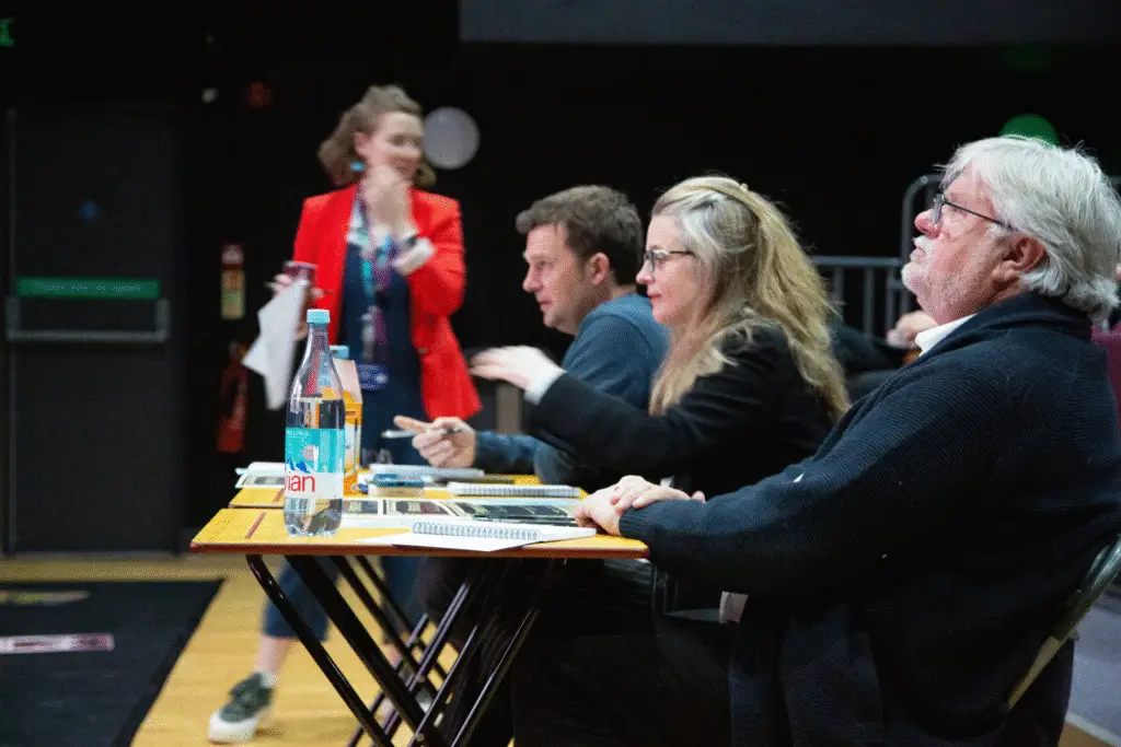 Judges seated at a table making notes during screenings.