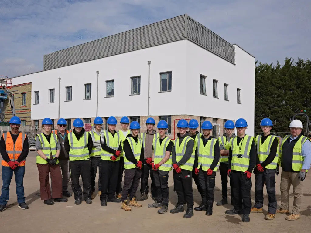 A group of Construction students in hard hats and high-visibility jackets standing outside the new Trowbridge Integrated Care Centre during a site visit.
