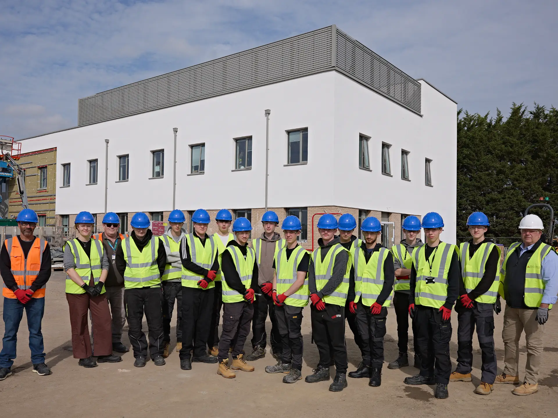 A group of Construction students in hard hats and high-visibility jackets standing outside the new Trowbridge Integrated Care Centre during a site visit.