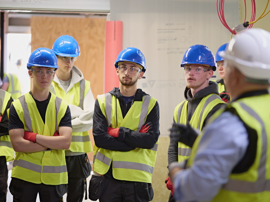Construction students in hi-vis jackets and hard hats listen to a site briefing inside the new Trowbridge Integrated Care Centre.