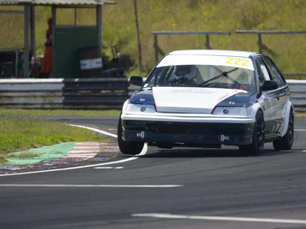 A race car prepared by Wiltshire College & University Centre Motorsport Engineering students taking a corner at Castle Combe Circuit.