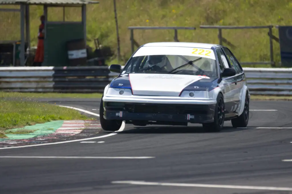 A race car prepared by Wiltshire College & University Centre Motorsport Engineering students taking a corner at Castle Combe Circuit.