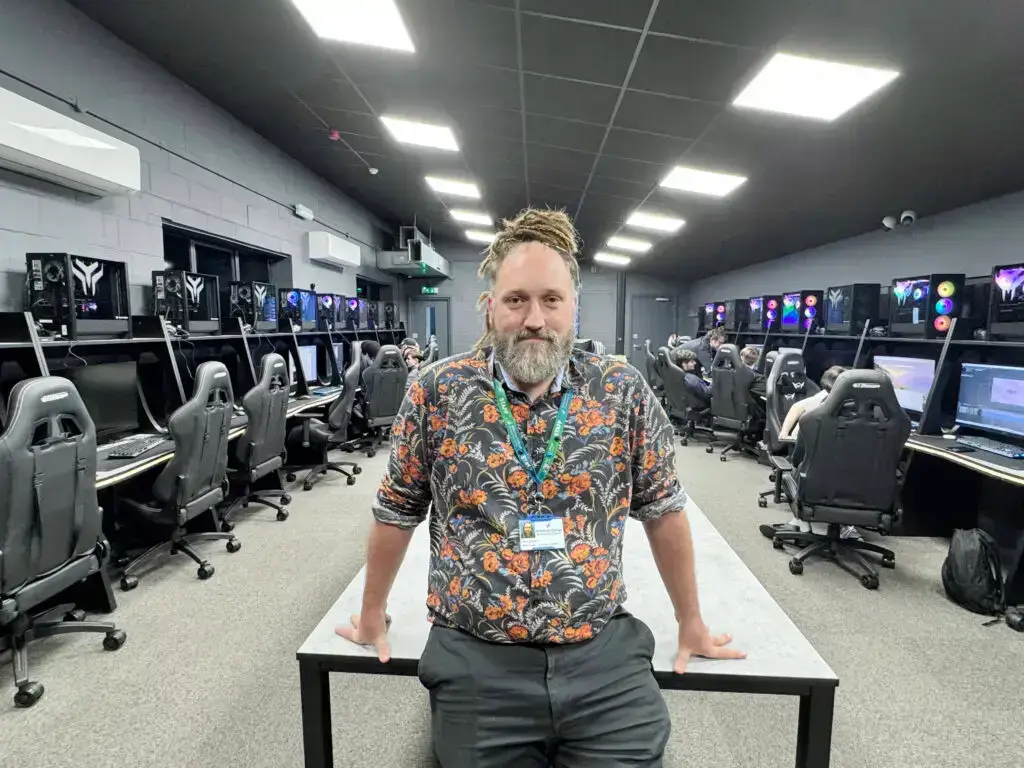Lecturer standing in the expanded modern digital suite at Tech Trowbridge, with students working at high-spec computers for Games Development and eSports courses.