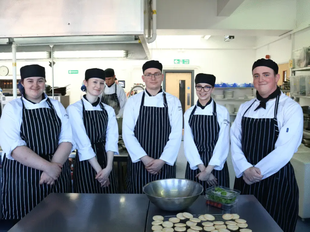 A group of hospitality students standing together in their chef whites.