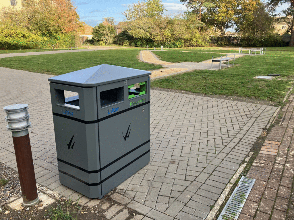 A grey litter and recycling bin beside paved walkways and lawns in the newly landscaped courtyard at Wiltshire College & University Centre’s Trowbridge campus.