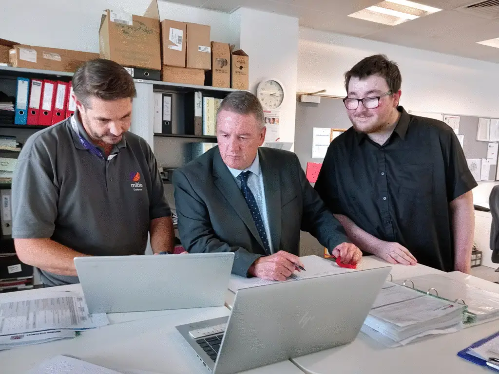 Three people in an office reviewing documents and laptops together during a T Level placement activity at Mitie’s MOD Corsham site.