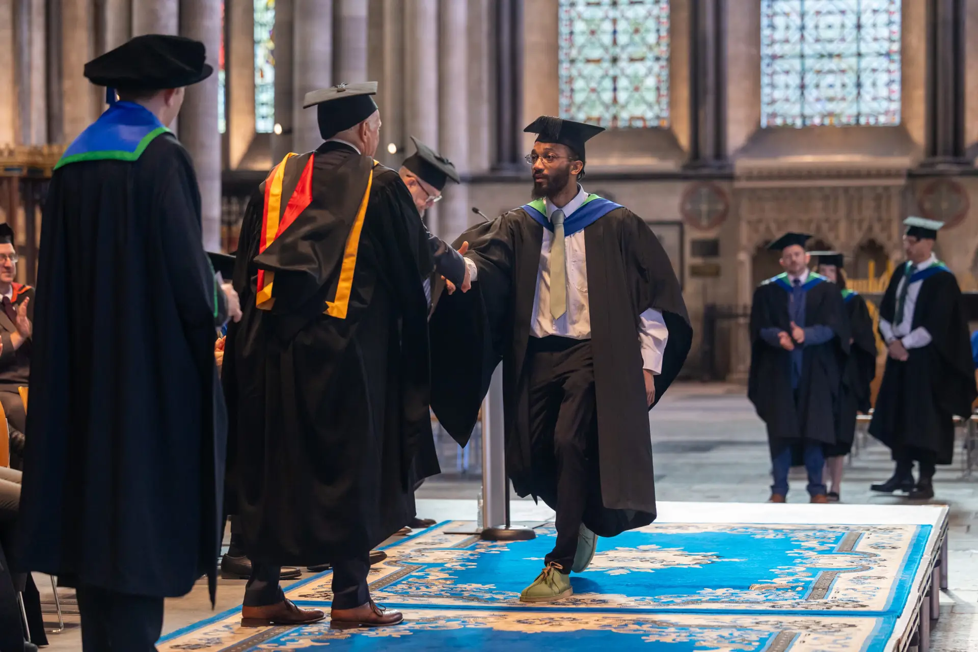 Higher education student walking across the stage and shaking hands with lecturer.