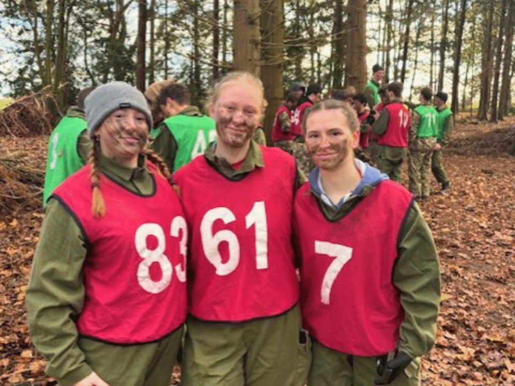 Three students wearing numbered training bibs pose together outdoors during a practical session.