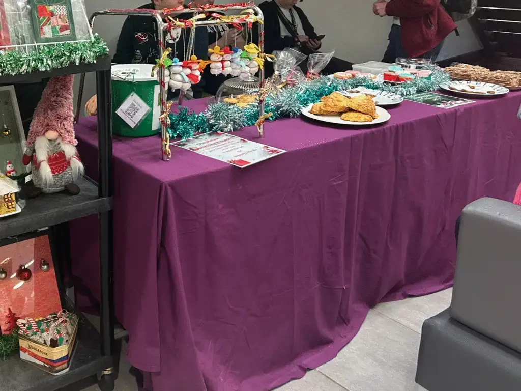 A festive table display of homemade cakes and treats for sale at a charity bake sale.