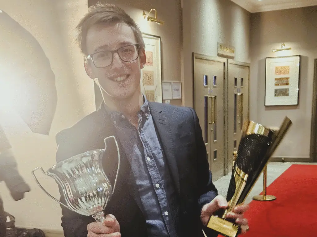 A lecturer from Wiltshire College & University Centre smiles while holding two motorsport trophies at the Castle Combe Racing Club Awards.