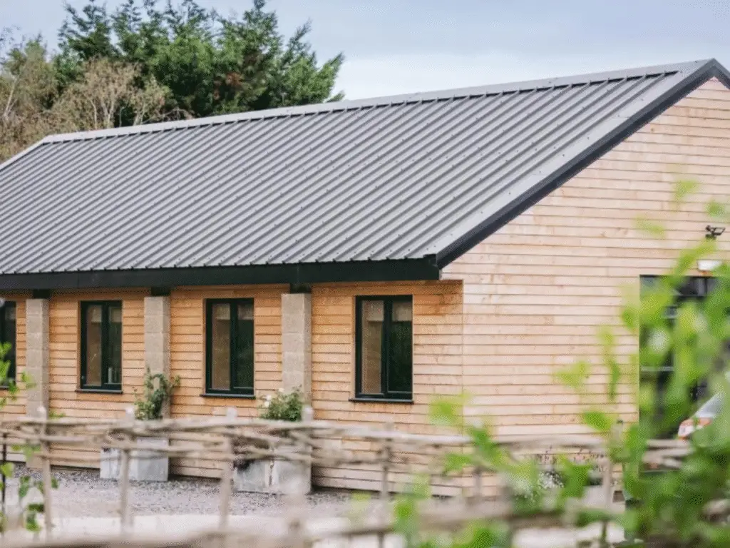 Timber-clad building at Great Cotmarsh Farm, surrounded by trees and countryside.