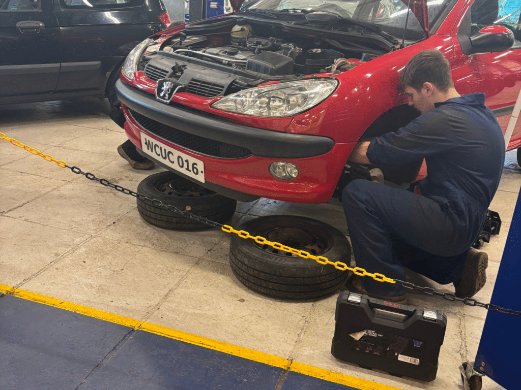 Automotive student carrying out maintenance work on a vehicle in the College workshop.
