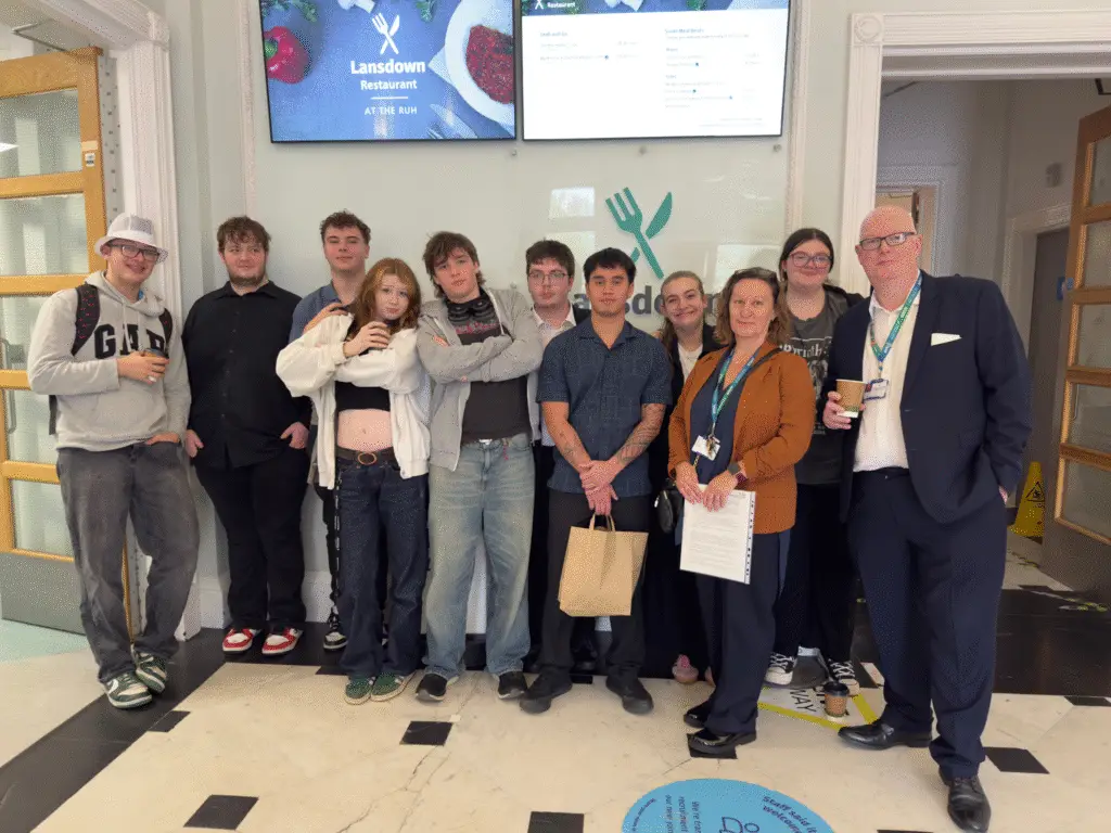 Group of hospitality students and staff standing together inside the Royal United Hospital catering area during an educational visit.