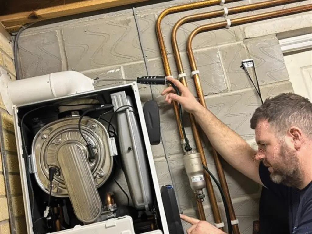 Plumbing apprentice examining internal boiler layout and pipe connections.