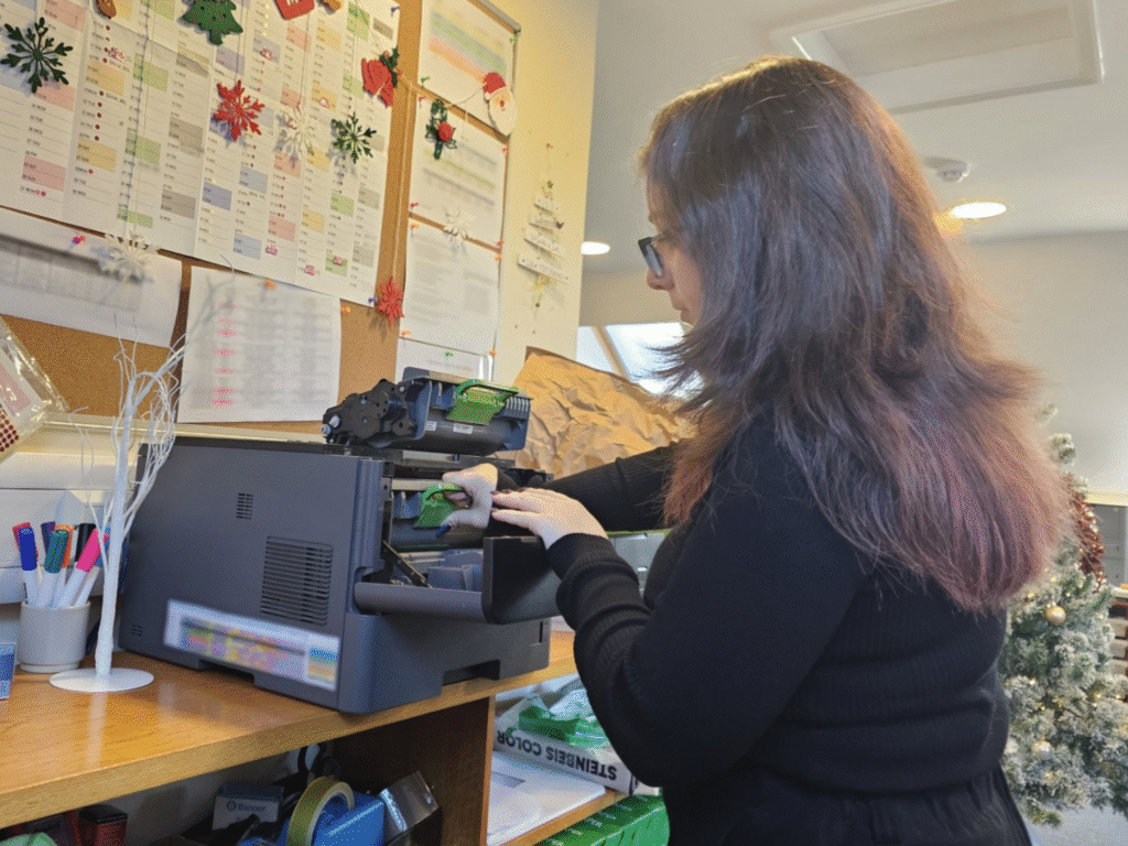 An ICT apprentice working on office equipment at a desk.