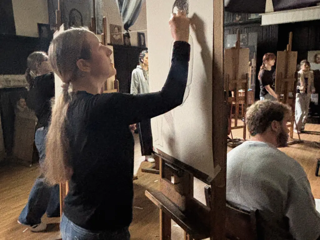A student concentrating on a charcoal life drawing at an easel during a studio-based session at Sarum Studio in Salisbury.