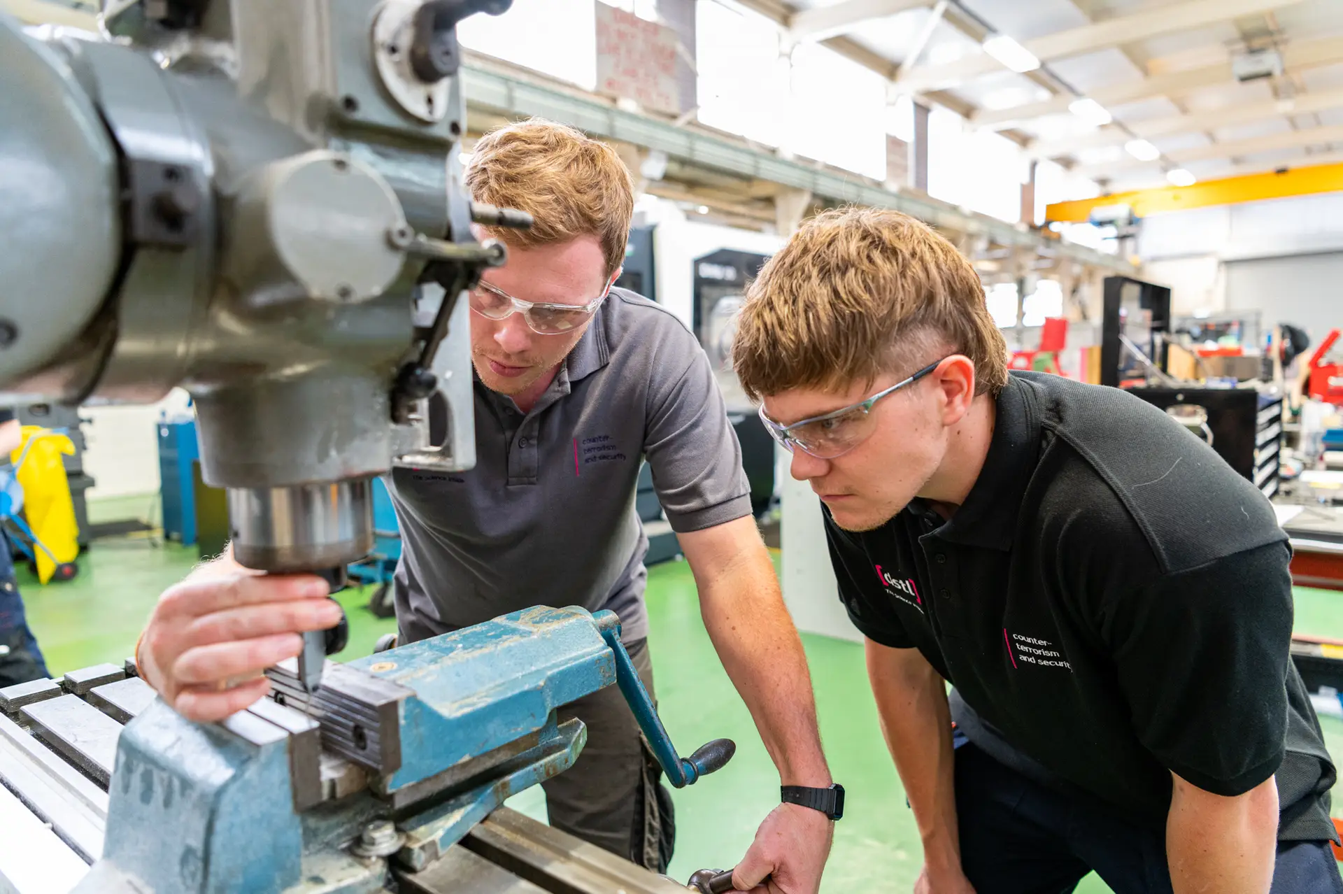 Apprentice working on some equipment with an employer observing and guiding him.