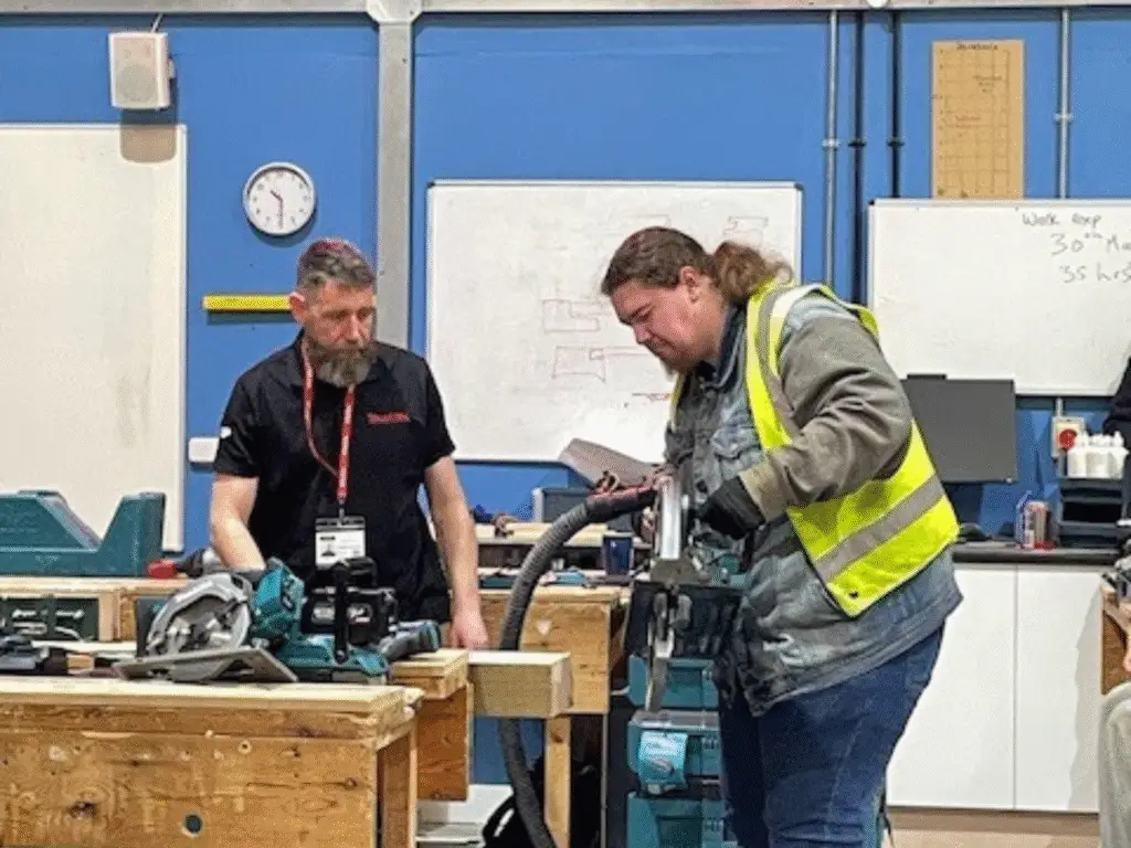 An apprentice using a power tool under the guidance of an expert.