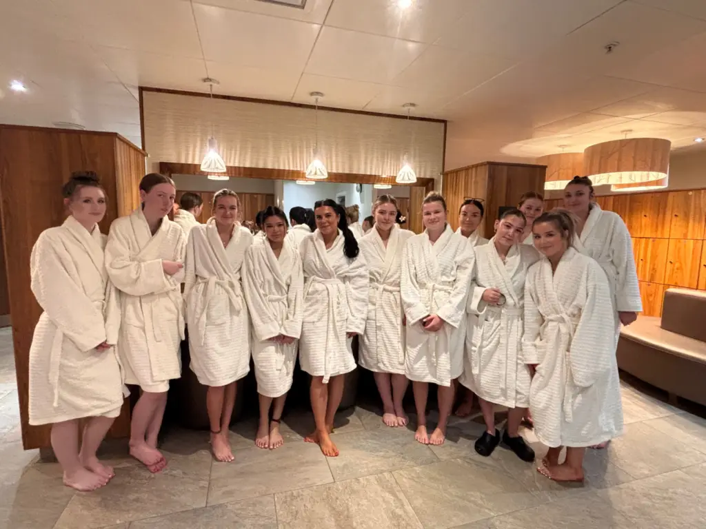 A group of beauty students in robes in a salon changing room.