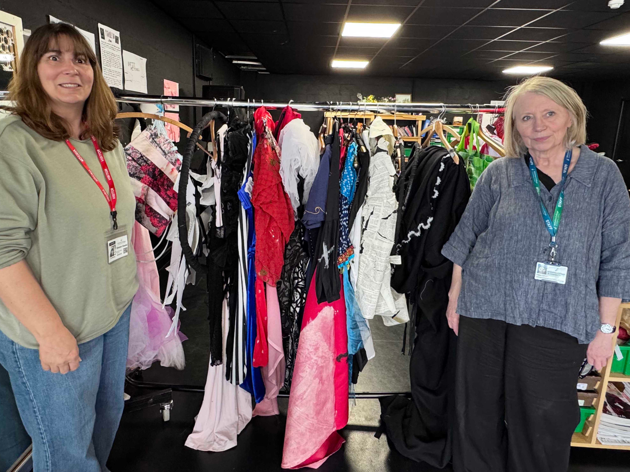 Two women standing next to rail of clothing made by students 