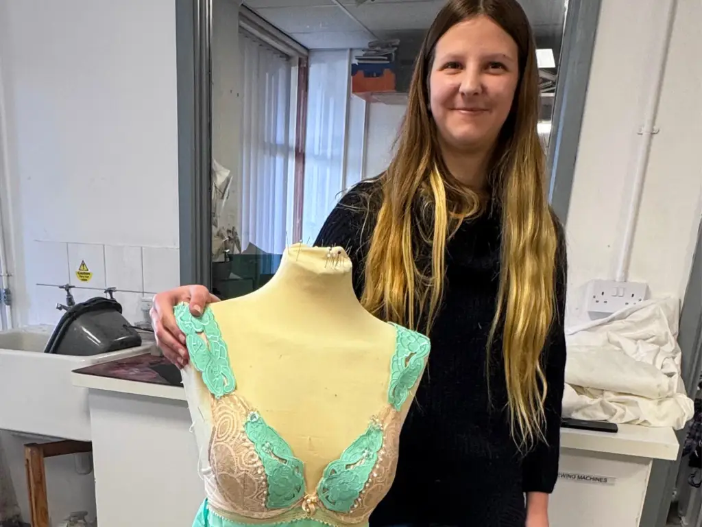 Student standing by a mannequin with her clothing displayed