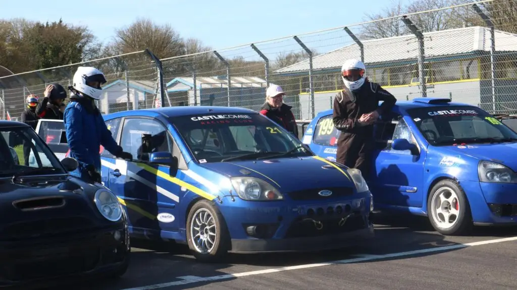 Close up of car on track with drivers around it with their helmets on
