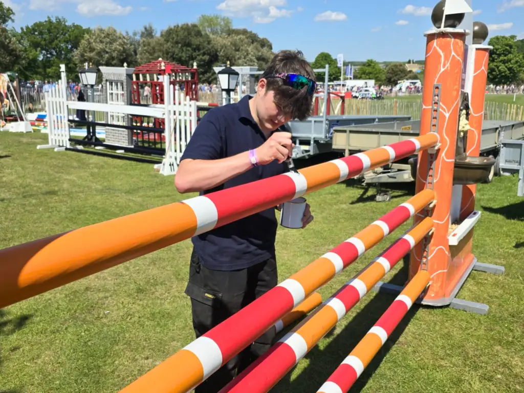 A student painting a fence at Badminton Horse Trials