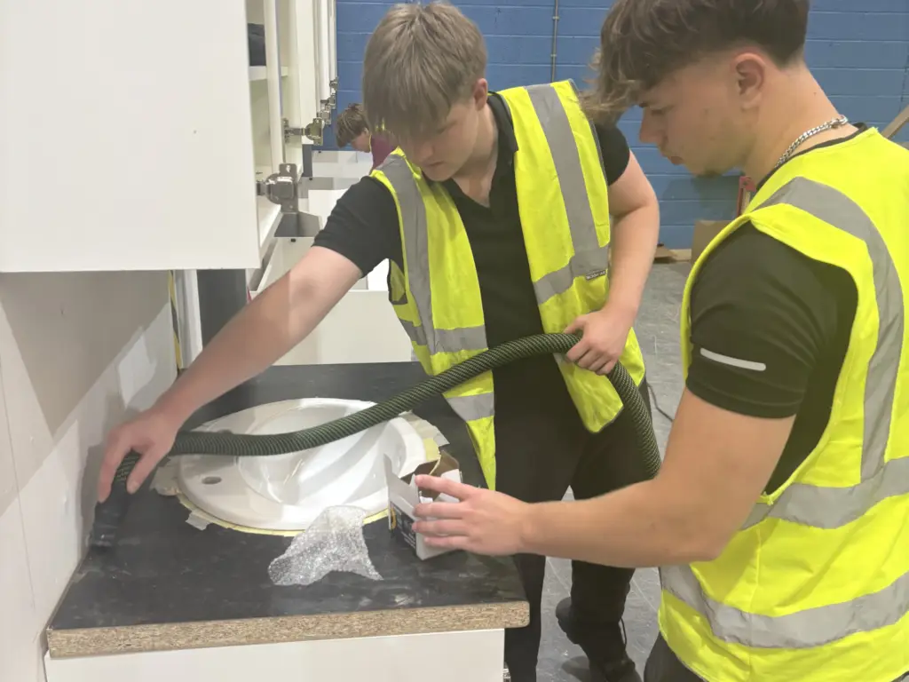 Construction students working together to install pipework during the College's Construction Skills Competition.