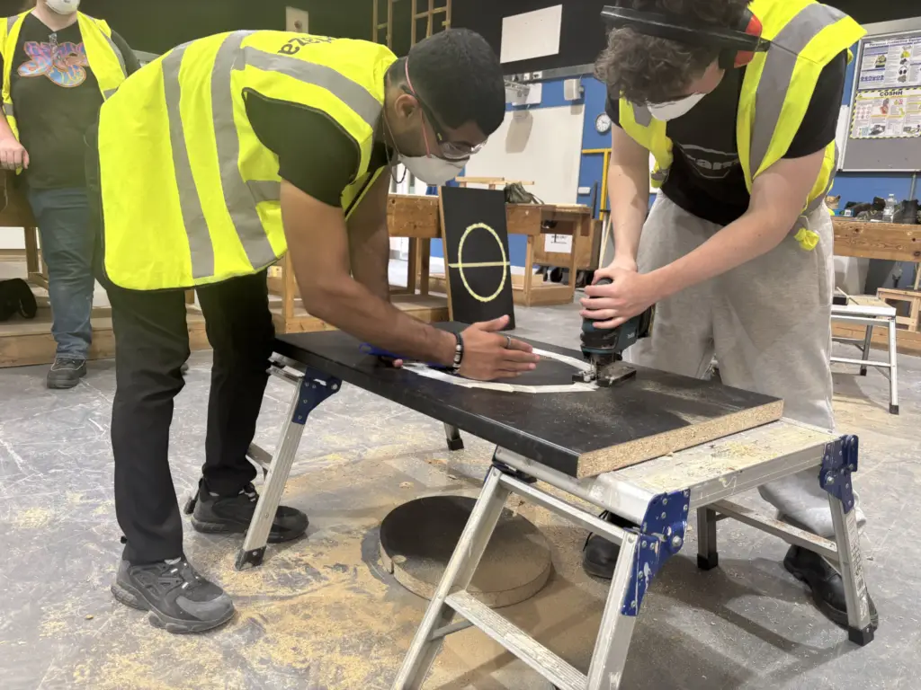 Two students working together with heavy machinery for the College's Construction Skills Competition.