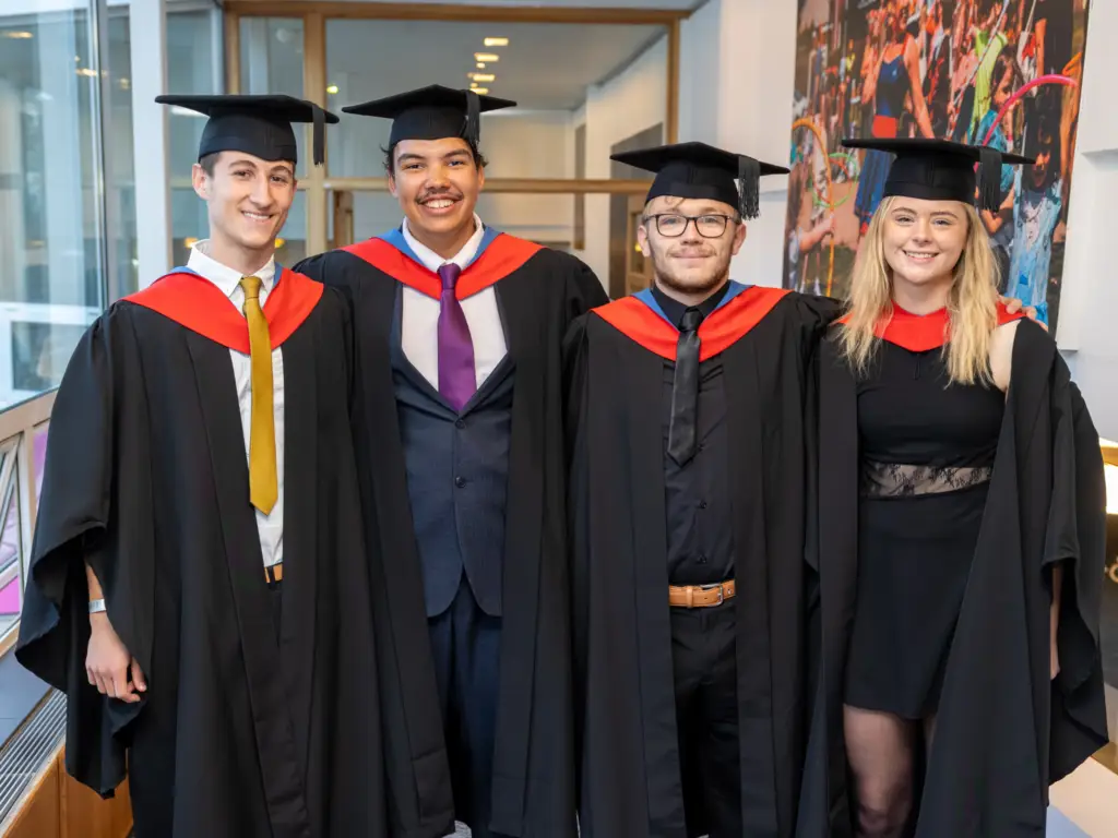 Four graduands and classmates post for a photo 