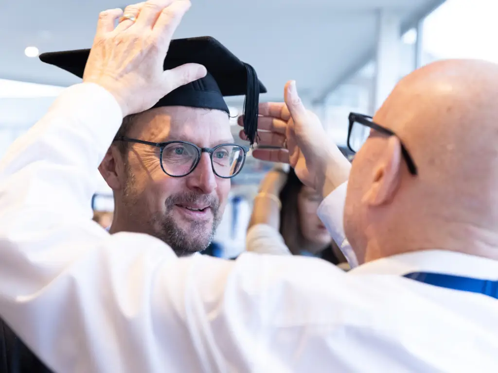 A Wiltshire College staff member getting his cap for graduation